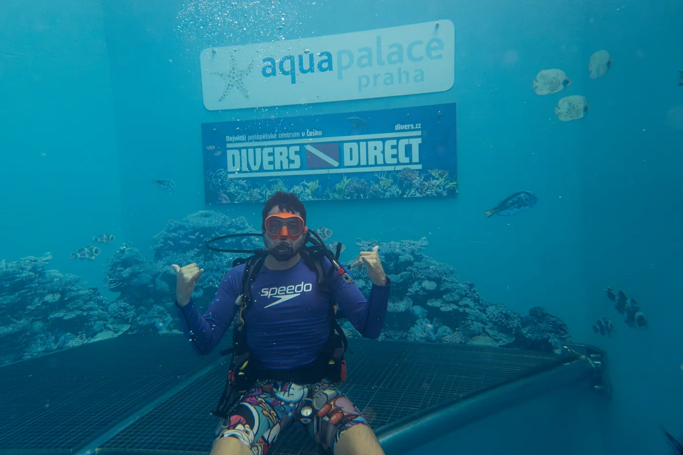 A diver in front of the Aquapalace Prague and Divers Direct signs at Jáma