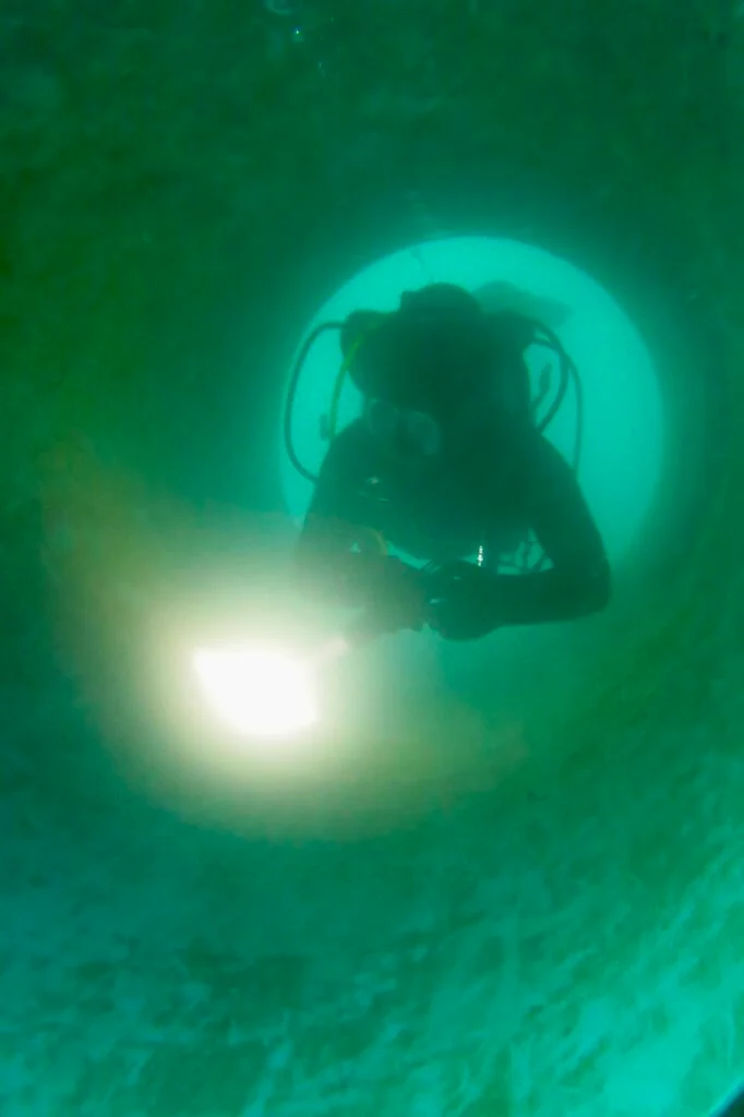A diver with a light during an inspection of a flooded corridor