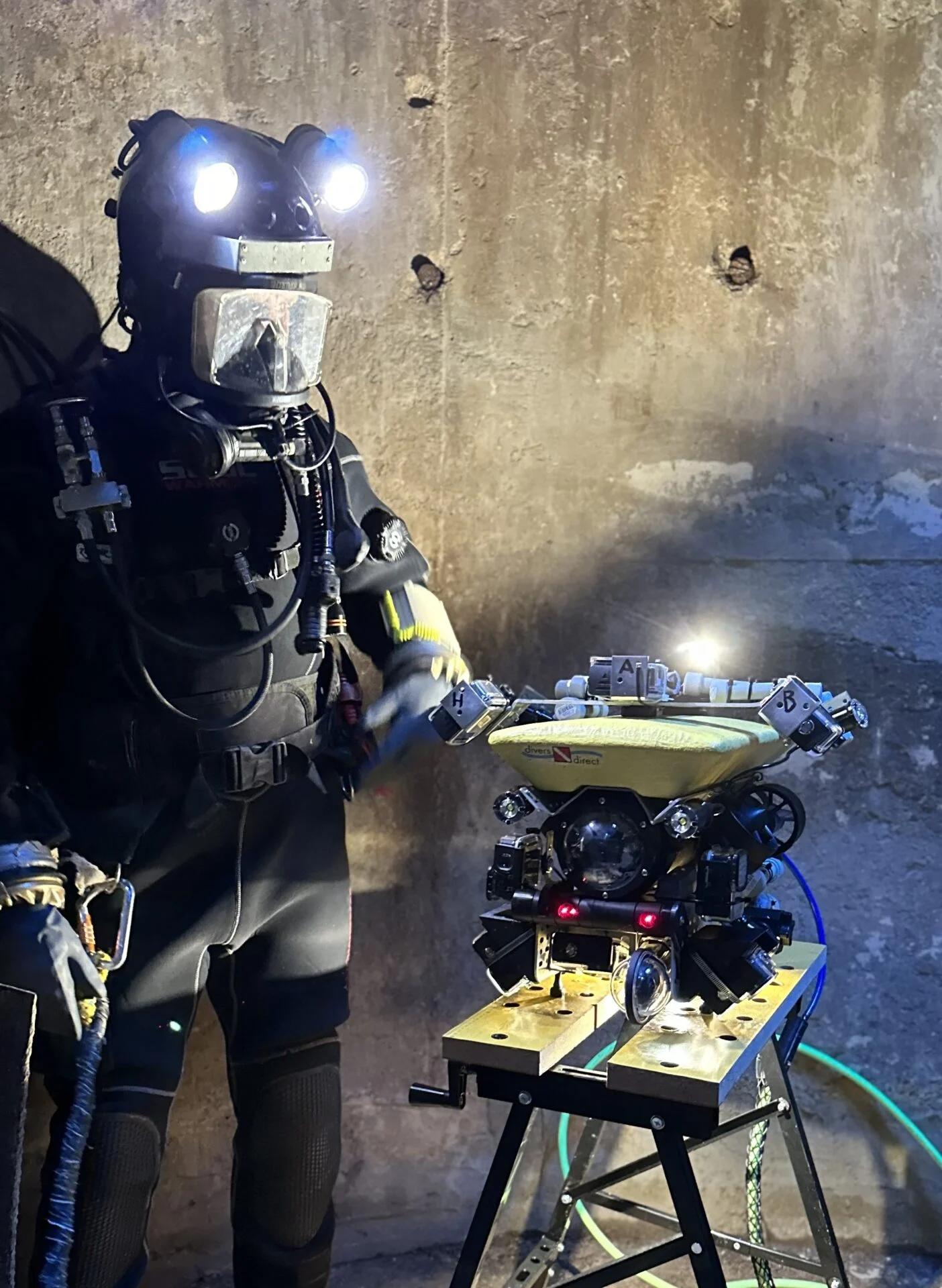 A diver in a helmet next to the yellow survey robot Robík